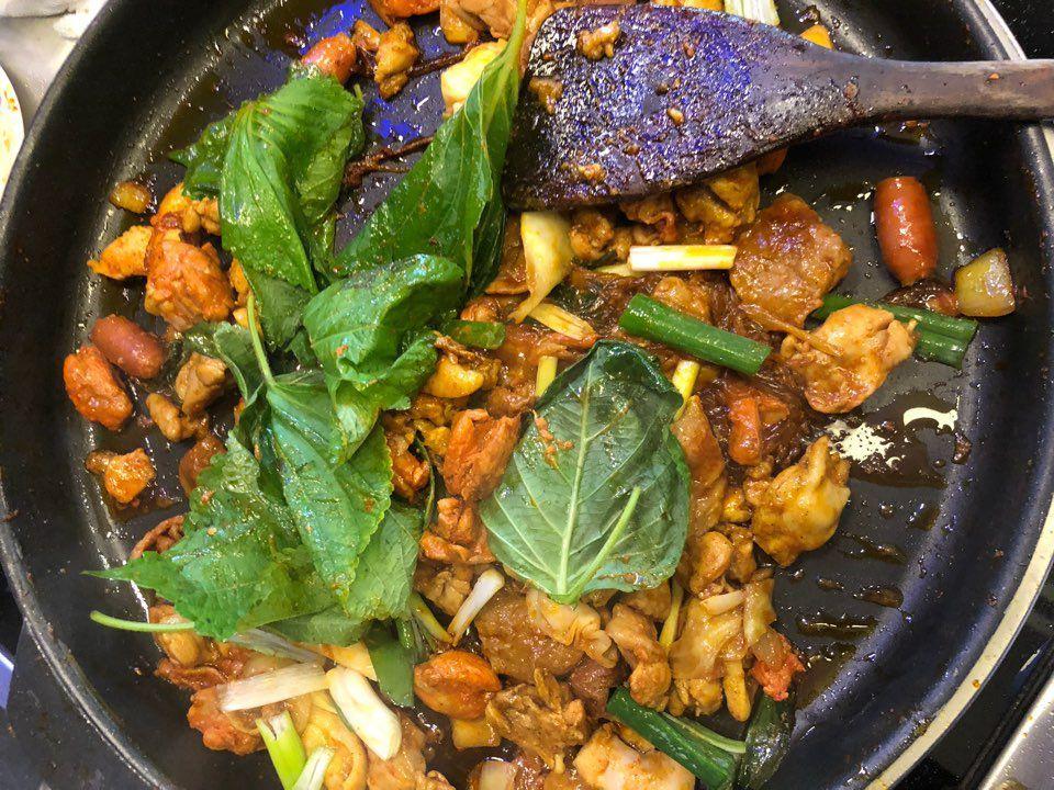 A sizzling pan of Dakgalbi, a spicy Korean stir-fry with chicken, vegetables and green leafy garnish, showing rich flavors and vibrant colors.